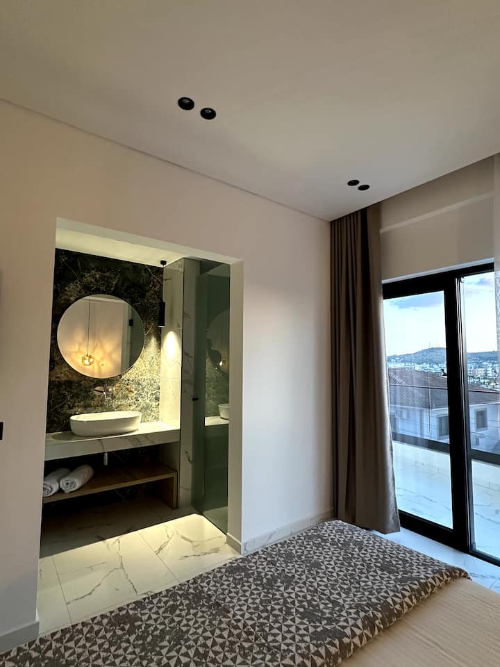 Private bathroom with round mirror and stone wall, seen from the room